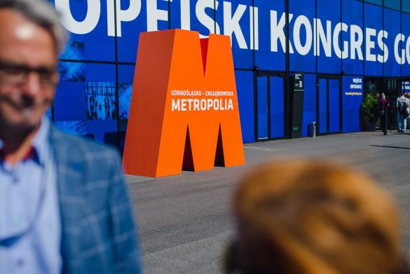 Pomarańczowa litera M stojąca przed budynkiem