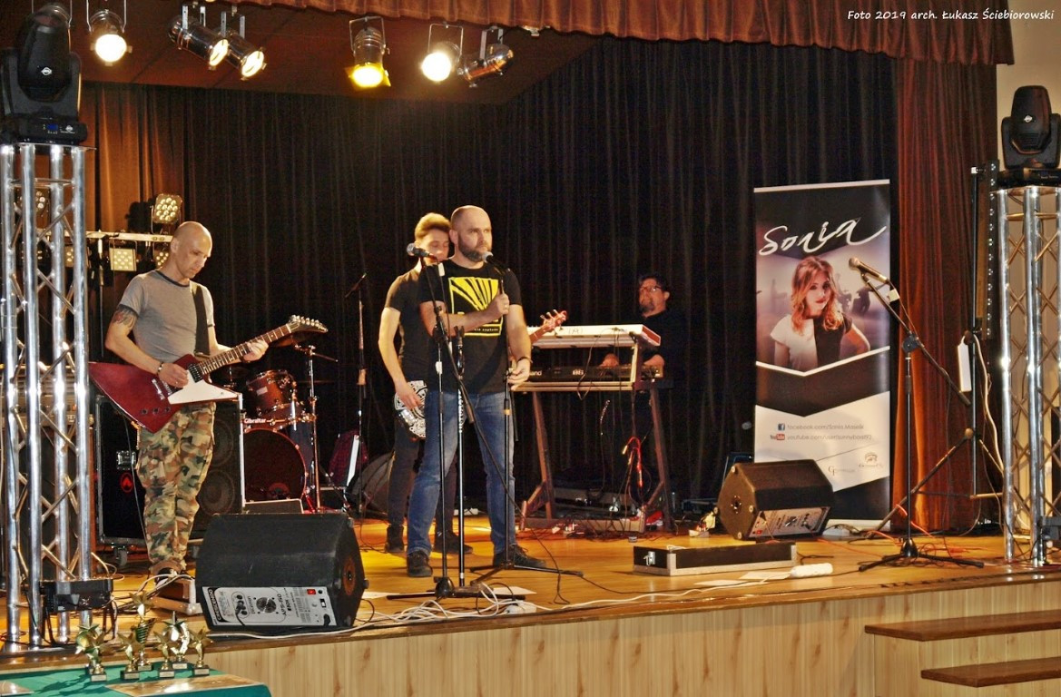 Mężczyźni stojący na scenie i wykonujący utwór muzyczny