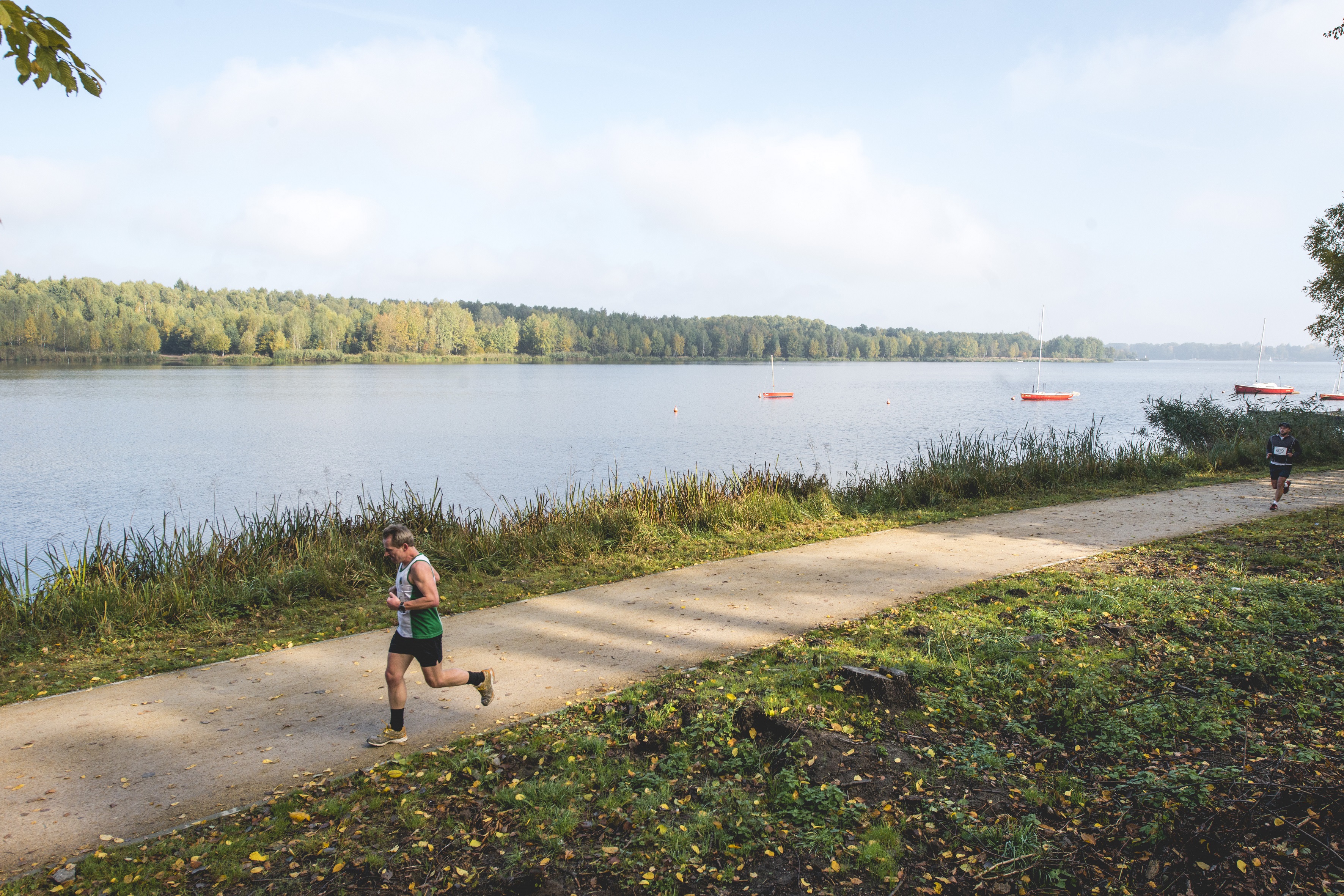 Biegacz uprawiający jogging ścieżką wzdłuż jeziora