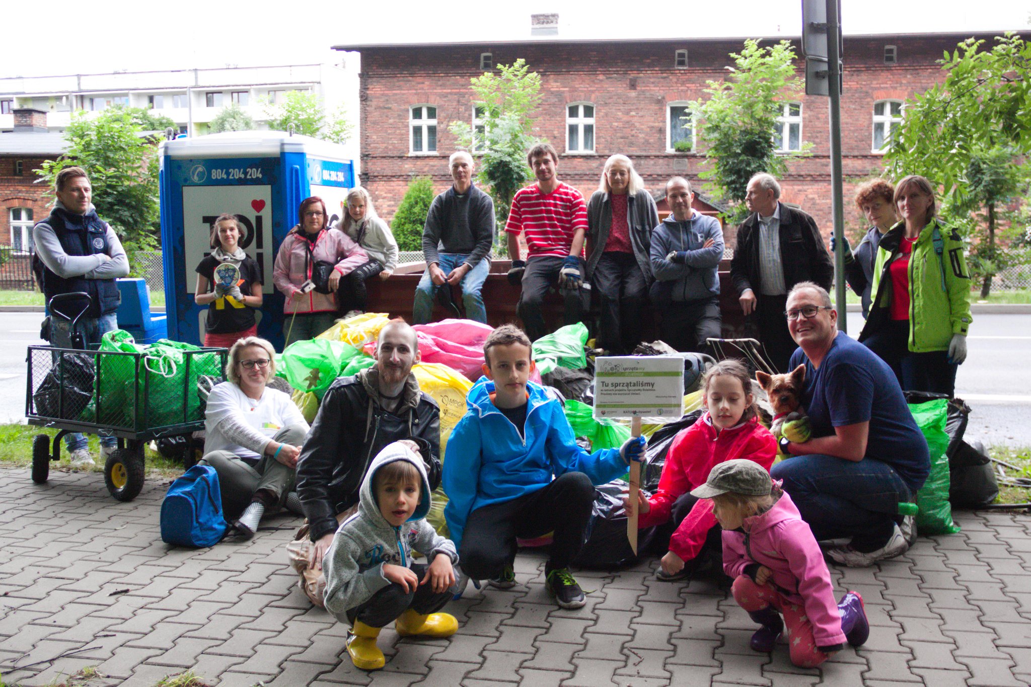 Grupa osób pozująca do zdjęcia z workami pełnymi śmieci po sprzątaniu obszaru miasta Katowice