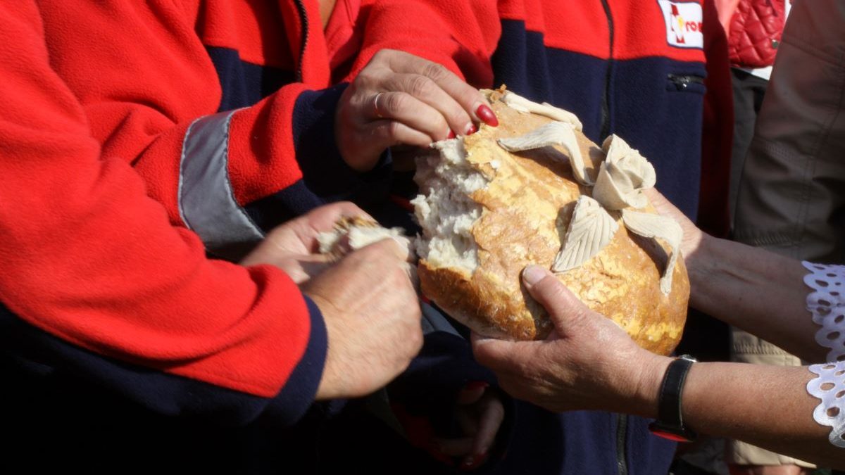 Zbliżenie dłoni osób dzielących się dożynkowym chlebem