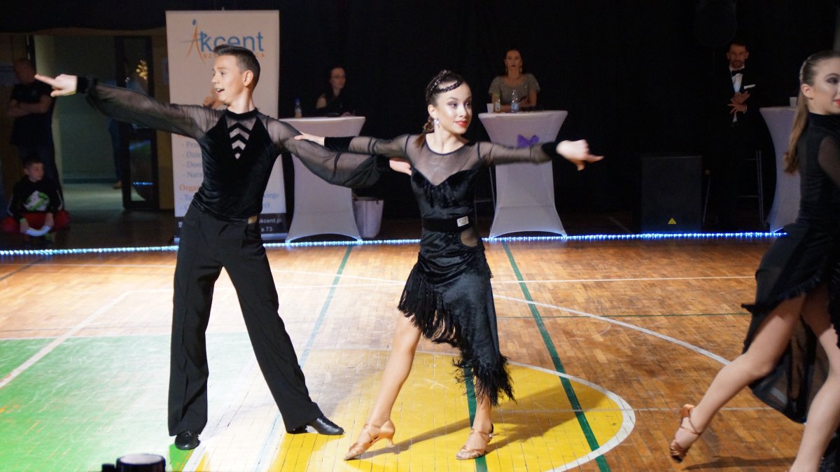 Para ubrana w czarne stroje tańcząca na parkiecie podczas konkursu tańca