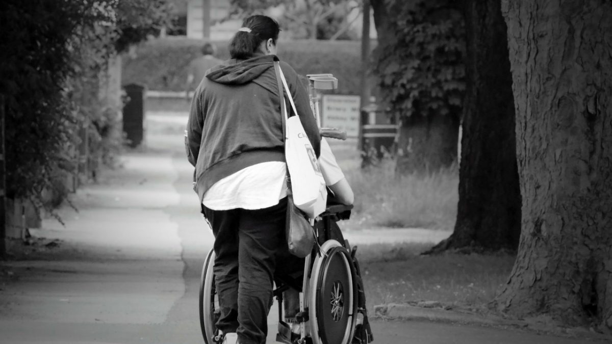 Kobieta kierująca wózkiem z osoba niepełnosprawną