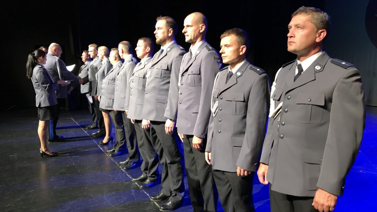 Grupa policjantów stojących w szeregu na scenie