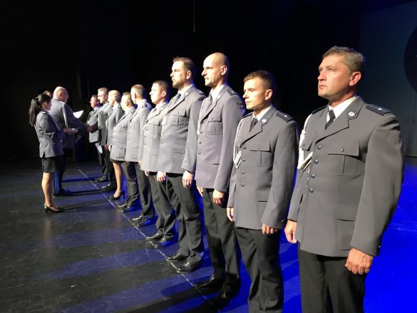 Grupa policjantów stojących w szeregu na scenie