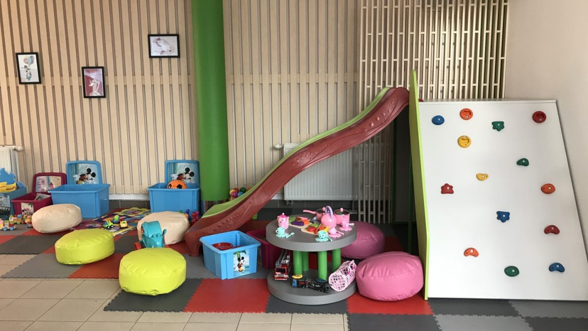Strefa zabaw dla dzieci ze zjeżdżalnią, zabawkami oraz małą ścianką do wspinaczki