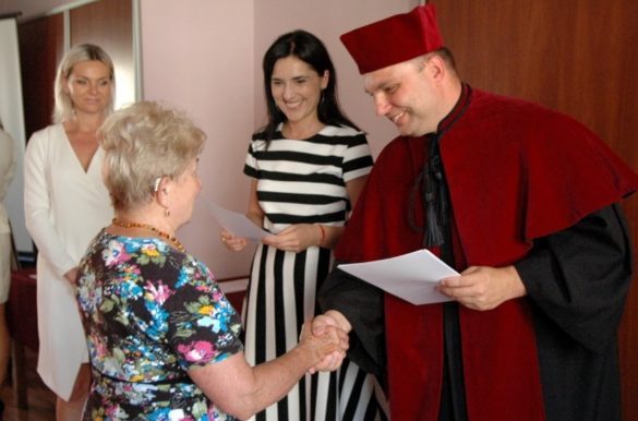 Dziekan wręcza dyplom seniorce