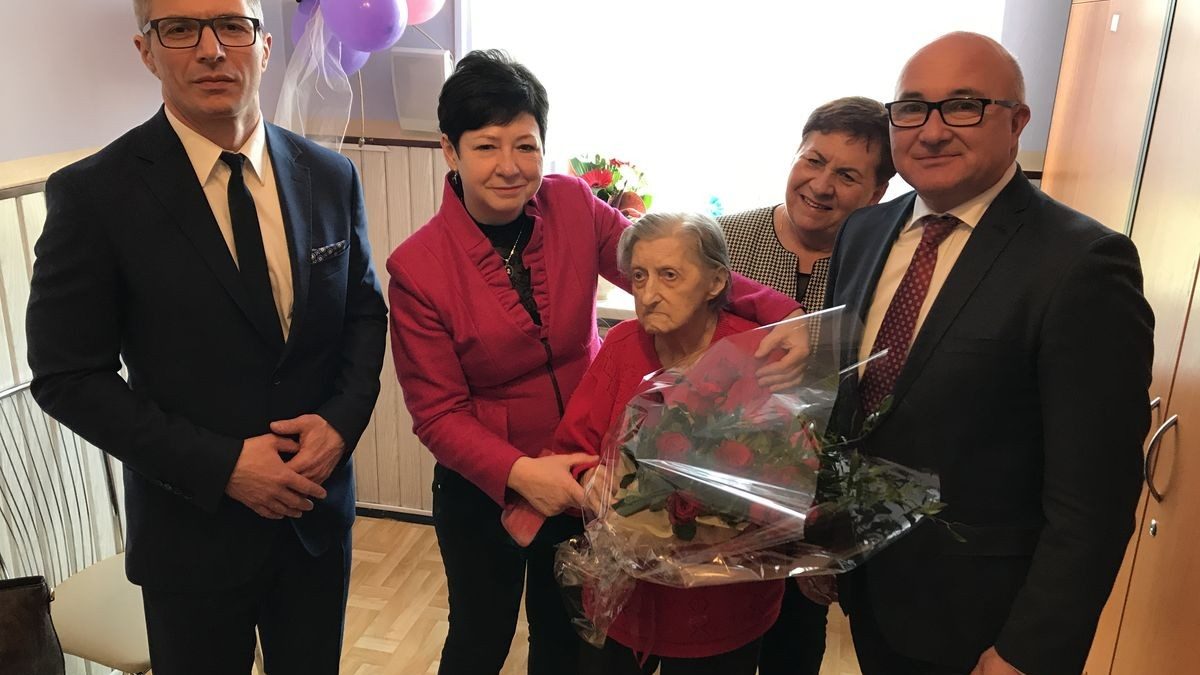 100-latka z kwiatami i towarzyszącymi osobami, m.in. prezydentem Chorzowa