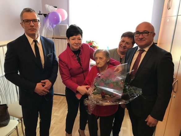 100-latka z kwiatami i towarzyszącymi osobami, m.in. prezydentem Chorzowa