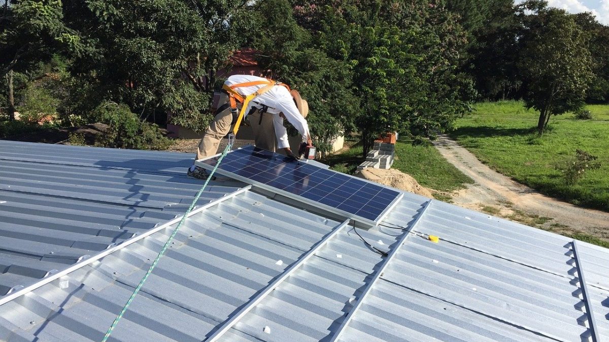 Mężczyzna montujący panel słoneczny na dachu