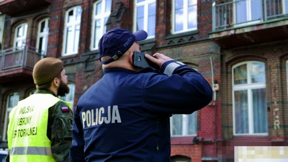 Policjant stojący przed blokiem mieszkalnym