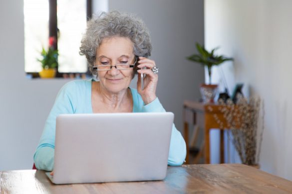 Seniorka z telefonem przy komputerze