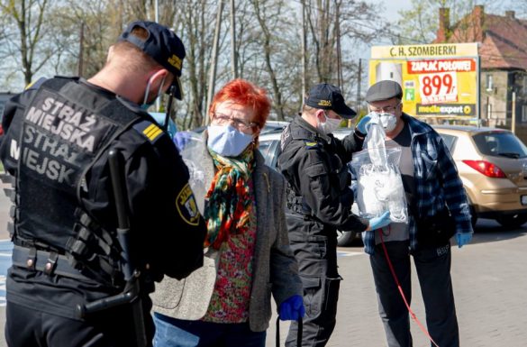 strażnicy miejscy rozdający maseczki