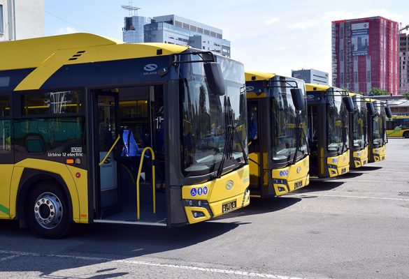 Pięć autobusów elektrycznych w żółtym kolorze, które ustawione są w szeregu na płycie zajezdni