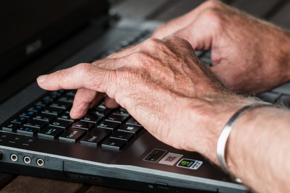 Ręce seniora na klawiaturze laptopa