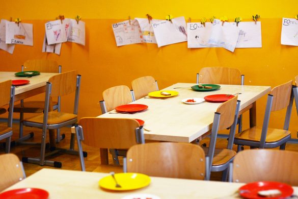 Wnętrzez przedszkola. Zdjęcie stolików i obrazków na ścianie.