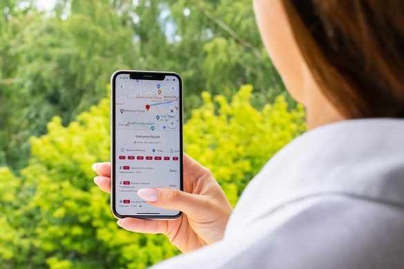 Kobieta trzyma w ręku telefon z wyświetlonym rozkładem jazdy w google map