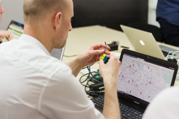 Uczestników warsztatów siedzi przed laptopem, na którym wyświetla sie mapa, a w rękach trzyma elementy towrzące czujnik jakości powietrza