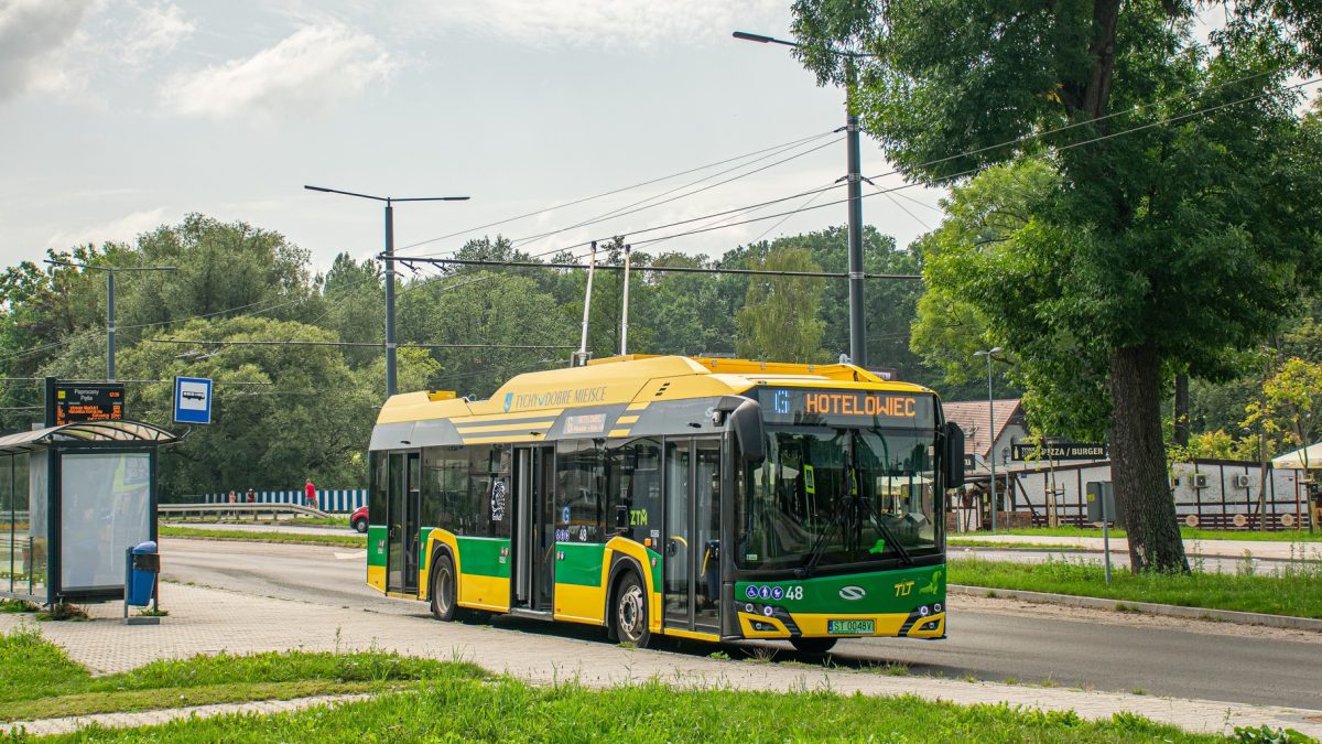 Zielono-żółty trolejbus jedzie ulicą