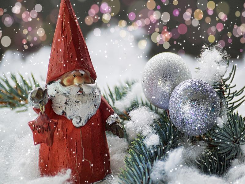 Figurka Św. Mikołaja obok stroika świątecznego z bombkami.