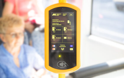 Widać mobilny, żółty biletomat w pojeździe komunikacji miejskiej GZM. Na ekranie wyświetlają się informacje o przystankach ("Katowice Superjednostka Dworzec", "Katowice Mikołowska") oraz opcje biletów czasowych (20, 40, 90 minut) i dziennego. Urządzenie obsługuje płatności zbliżeniowe kartami Visa, Mastercard i Maestro.
