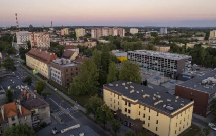 Zdjęcie przedstawia panoramę kampusu Politechniki Śląskiej w Zabrzu o zmierzchu. Widoczne są nowoczesne budynki uczelni, zieleń oraz miejska zabudowa.