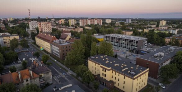 Zdjęcie przedstawia panoramę kampusu Politechniki Śląskiej w Zabrzu o zmierzchu. Widoczne są nowoczesne budynki uczelni, zieleń oraz miejska zabudowa.